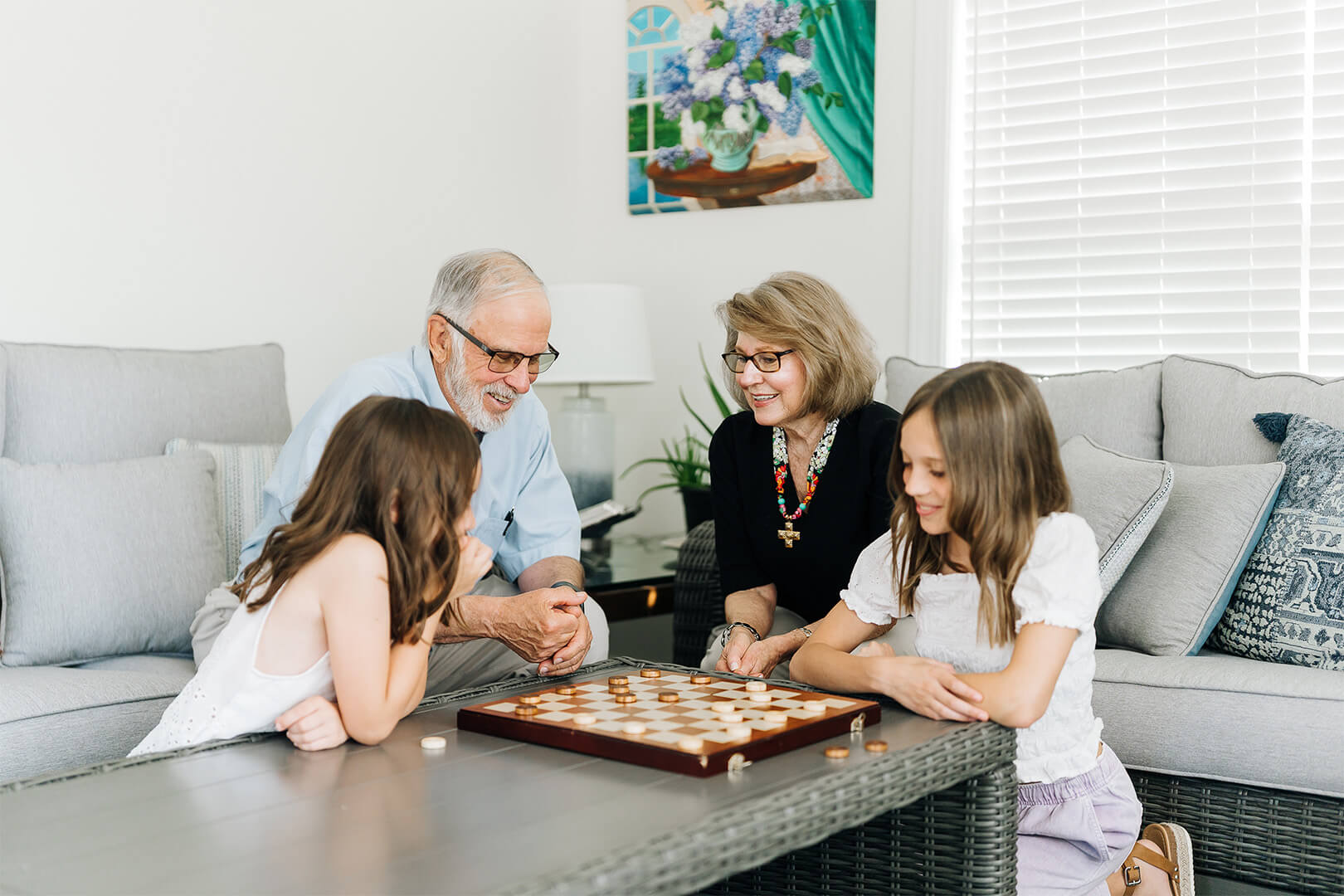 Grandparents and grandchildren play board game in a cozy living room setting.