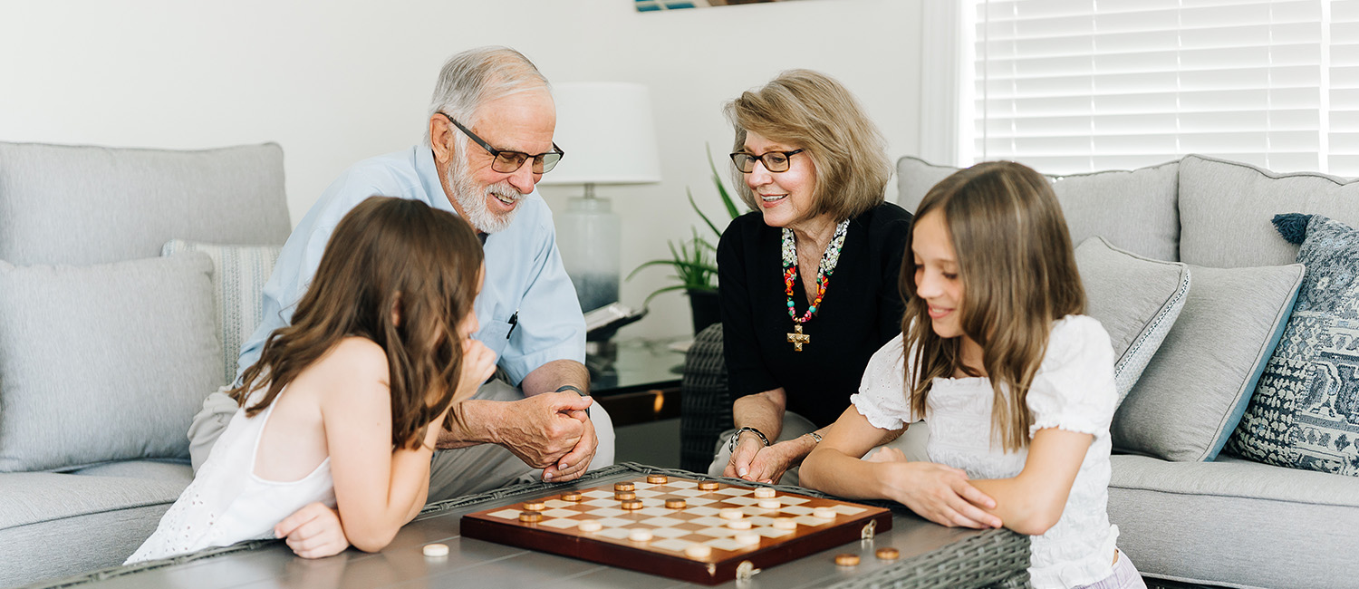 Grandkids and grandparents playing checkers at the coffee table