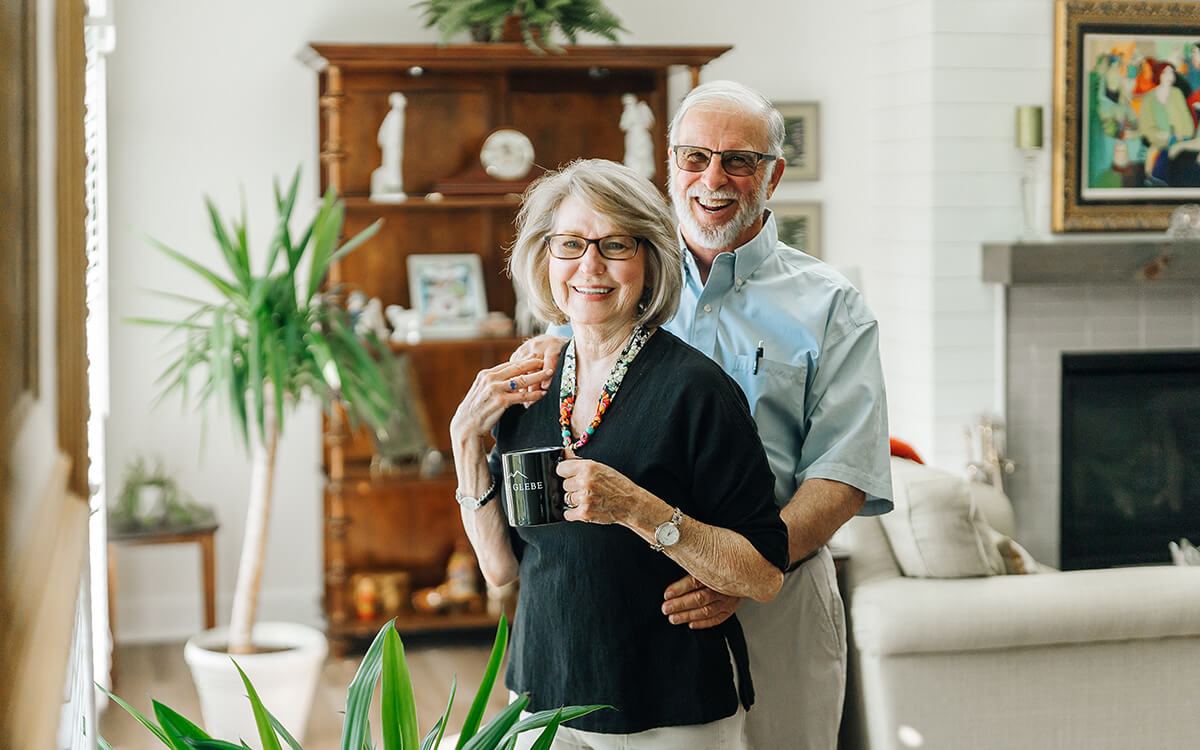 Smiling couple in cozy living room of their senior living unit.