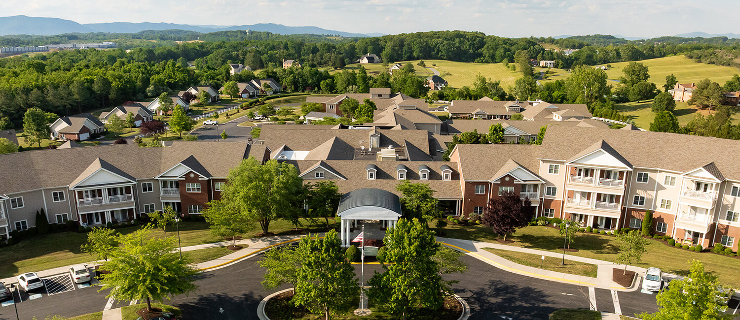 Aerial view of a senior living community surrounded by lush greenery and hills.