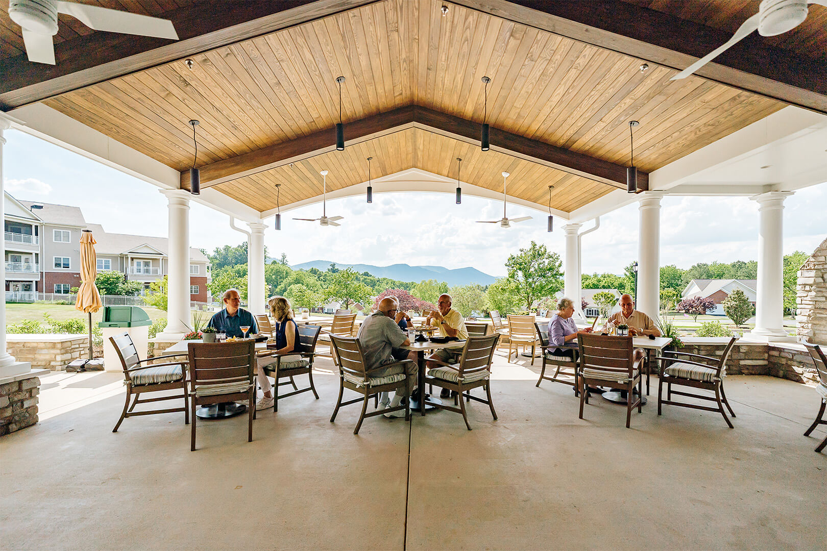 Seniors dining on a covered patio with mountain views in the background.