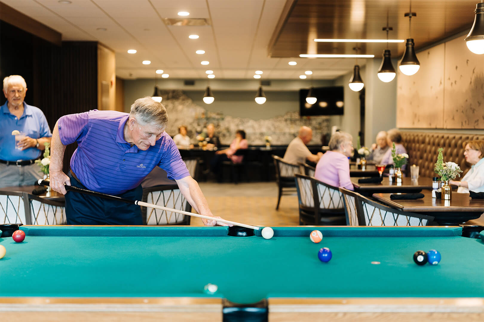 Seniors enjoying billiards and dining in a vibrant community center.