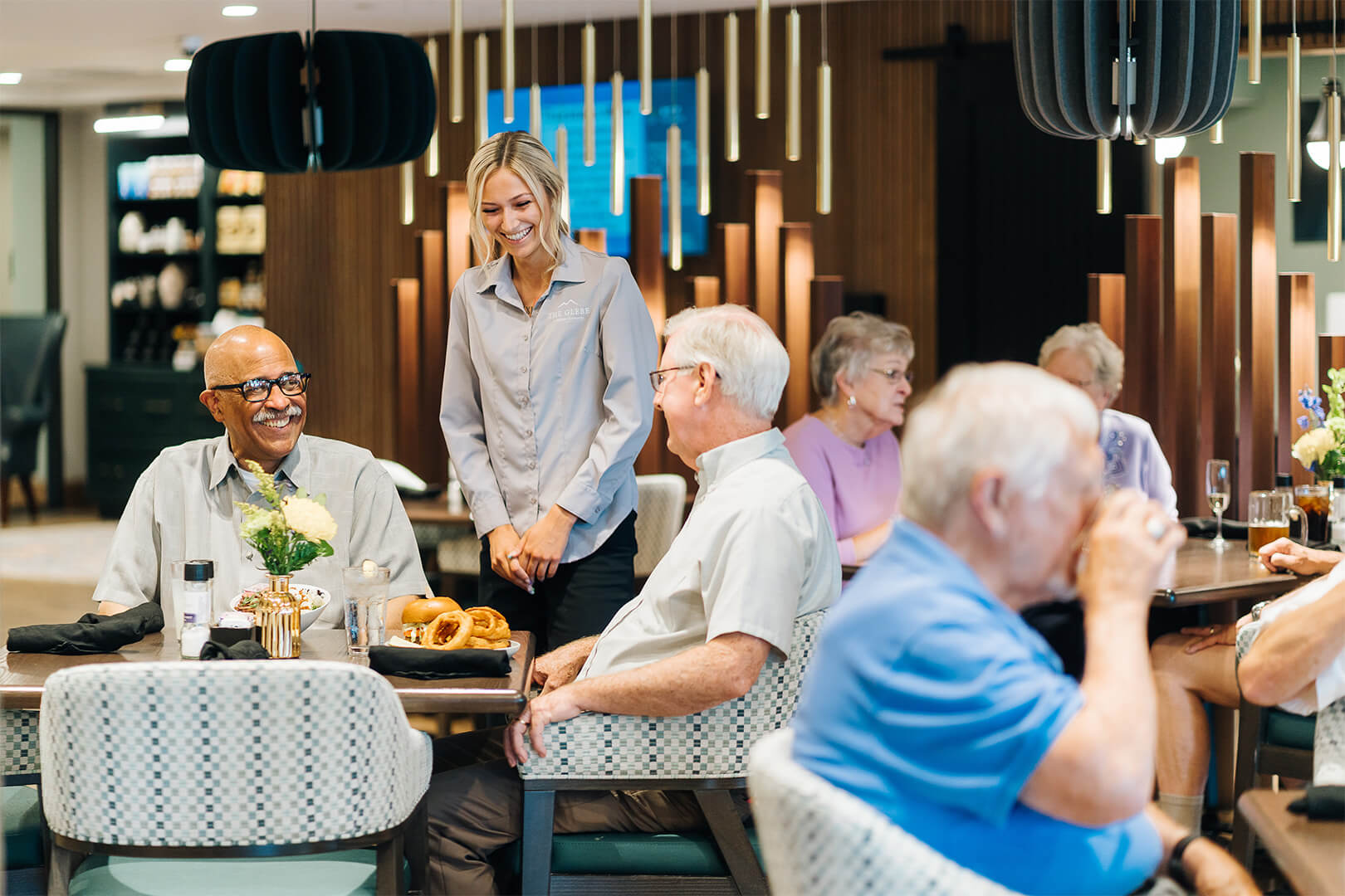 Residents and staff enjoy a meal in senior living dining area.