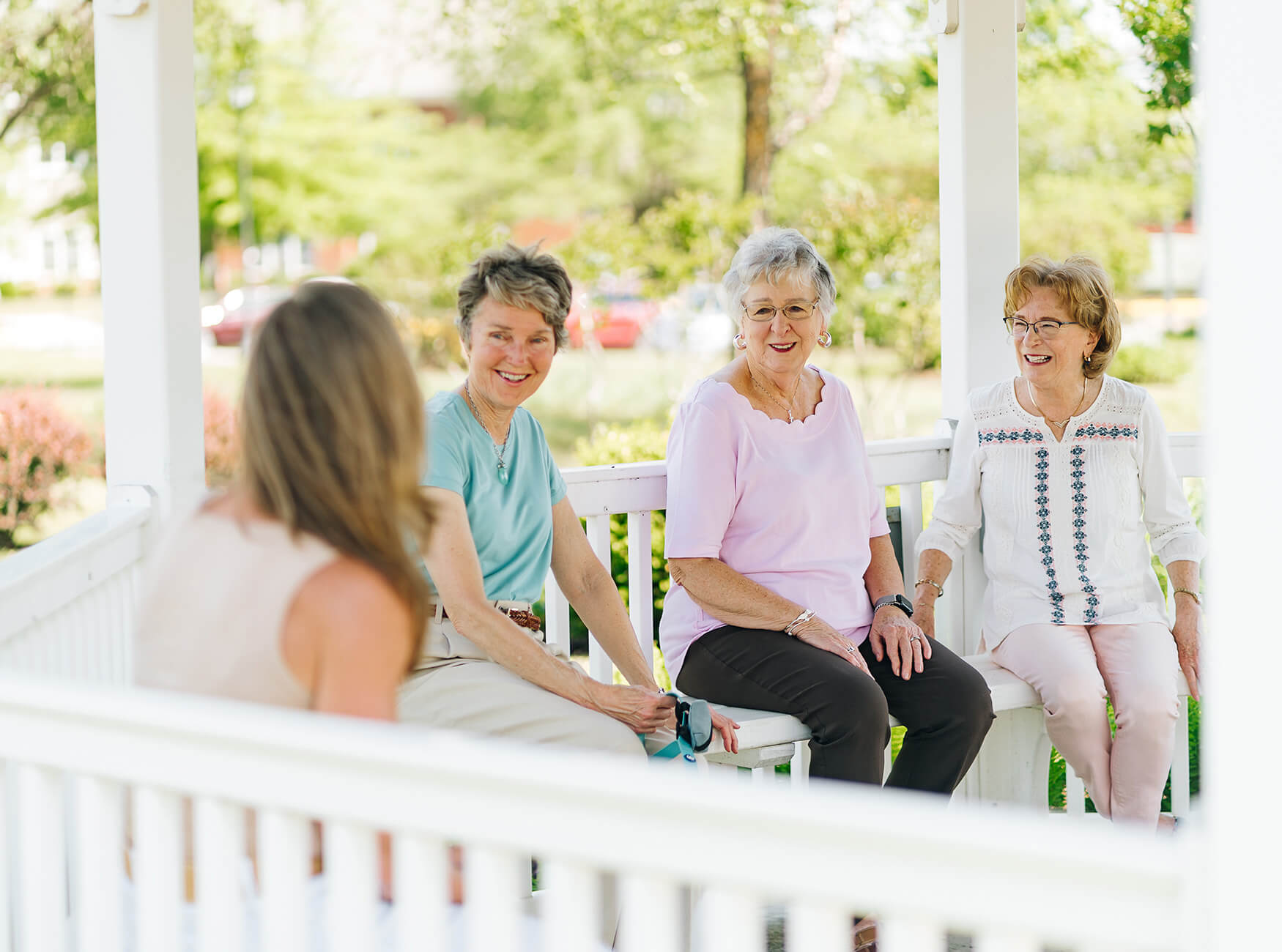 Group of elderly women enjoying conversation in a gazebo at a senior living community.