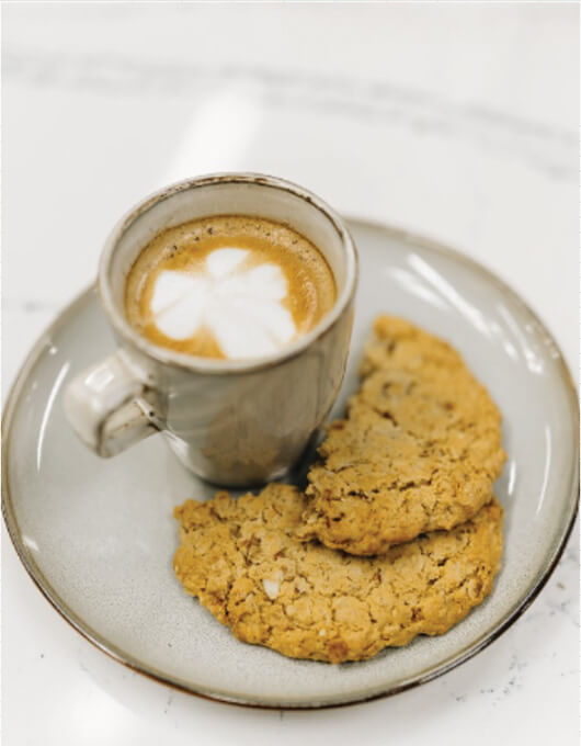 Coffee with latte art and two cookies on a white plate.