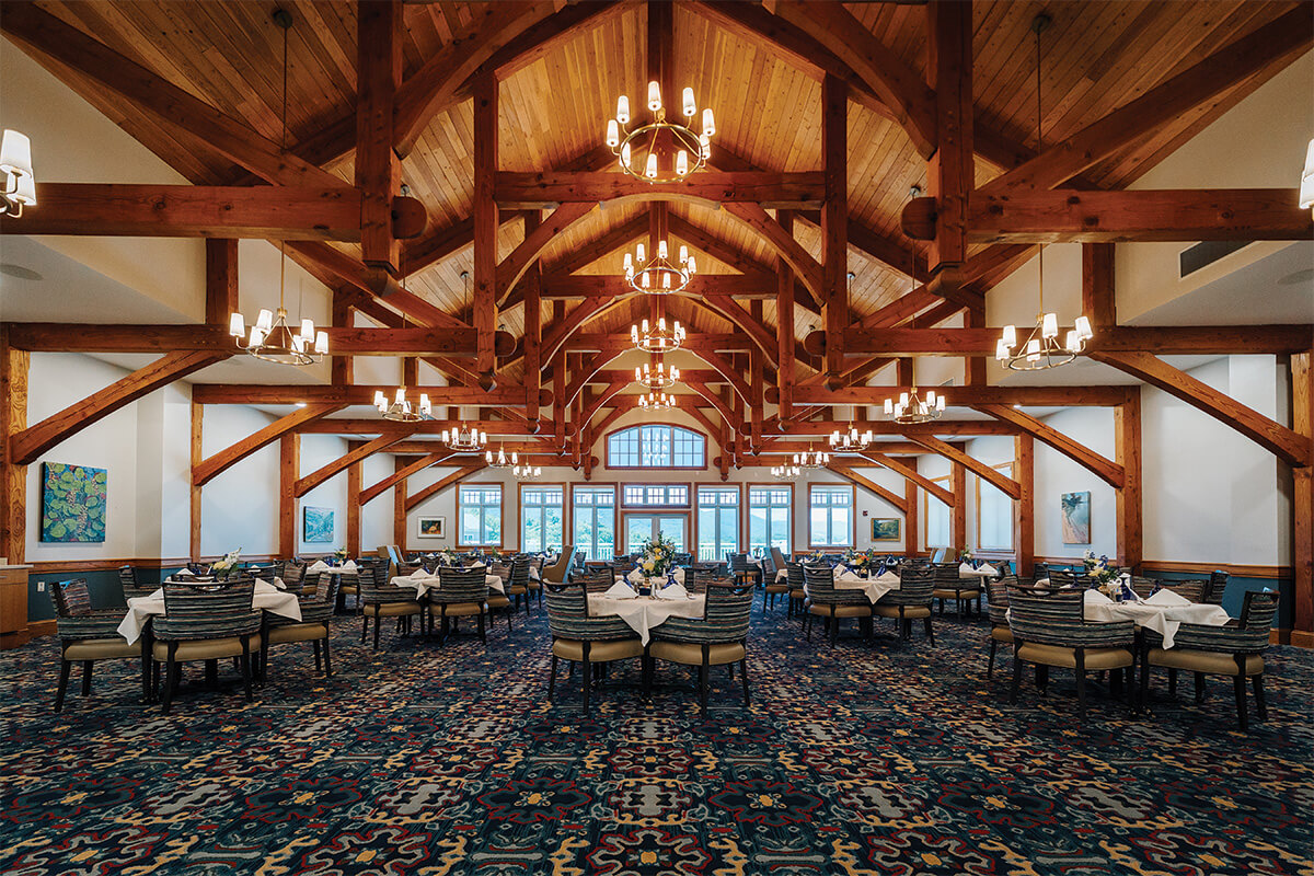Elegant dining hall with wooden beams and patterned carpet.