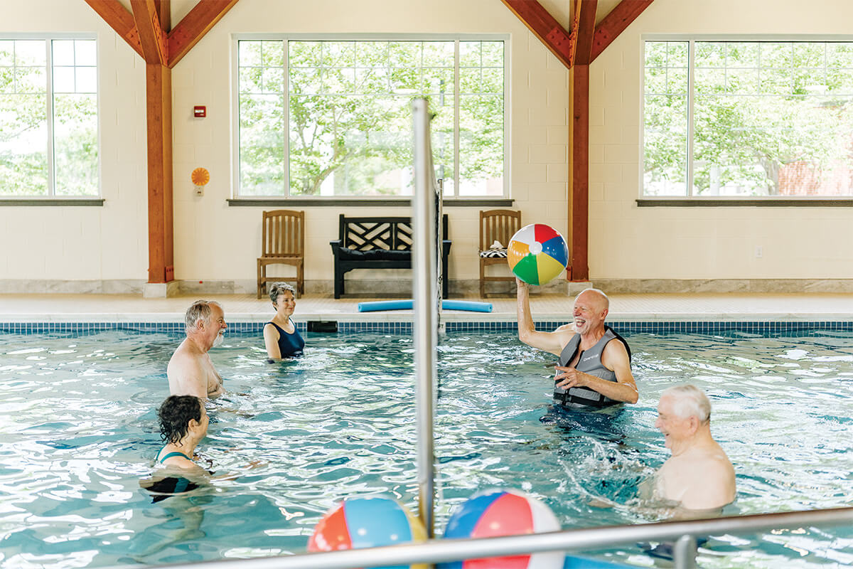 Seniors enjoying water activities in a community indoor pool.