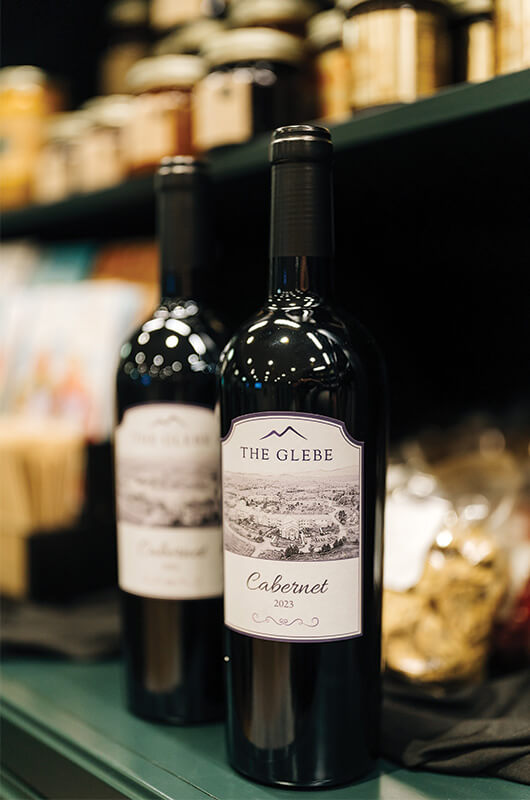 Two bottles of The Glebe Cabernet 2023 wine on a shelf.